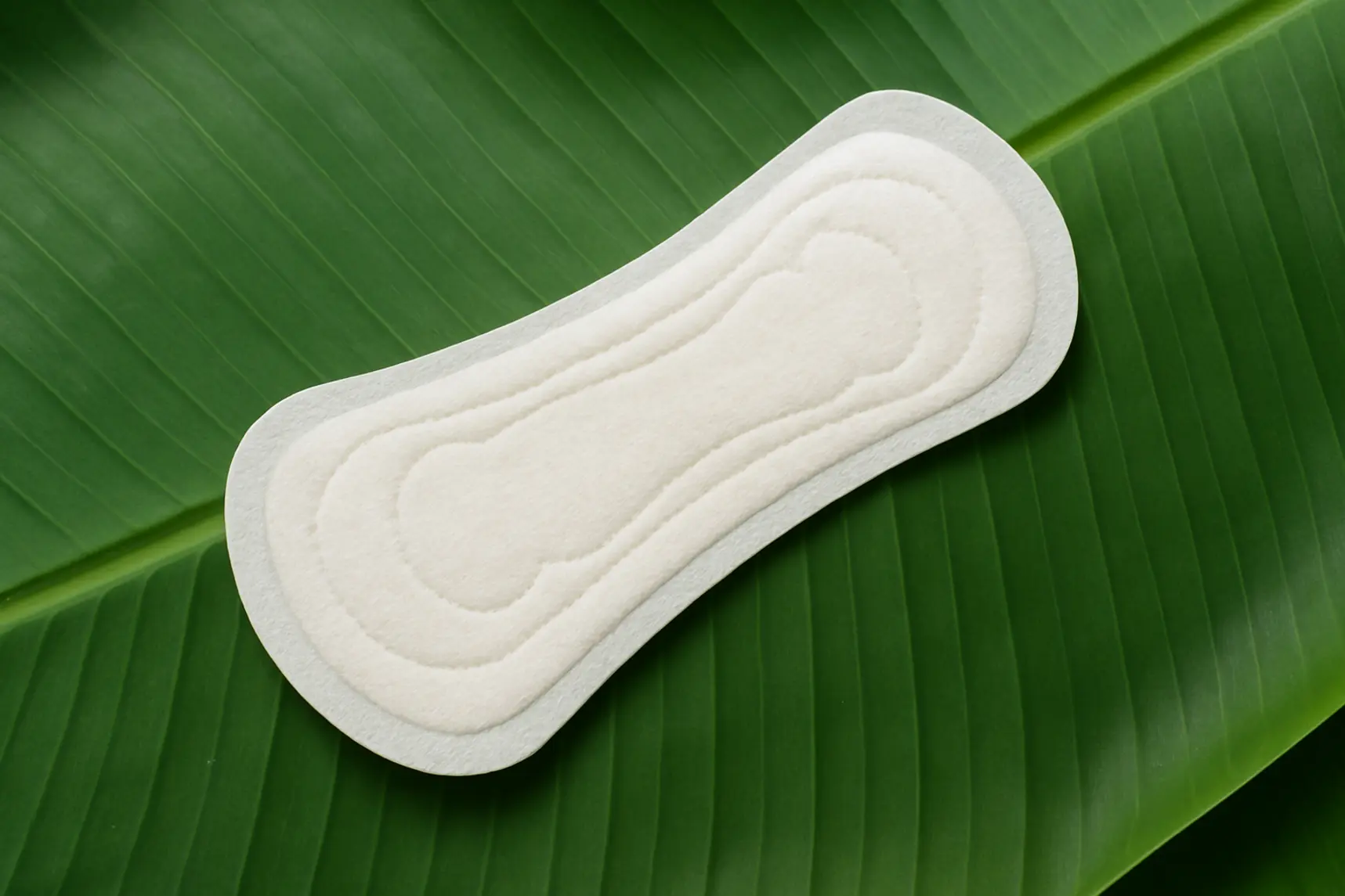 Assorbente Saathi in fibra di banana posato su foglia verde, senza plastica